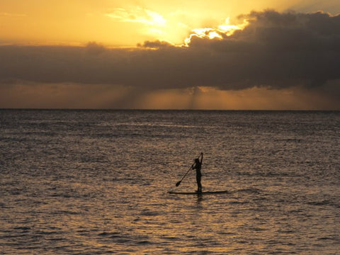 paddling a paddle board on sunset beach