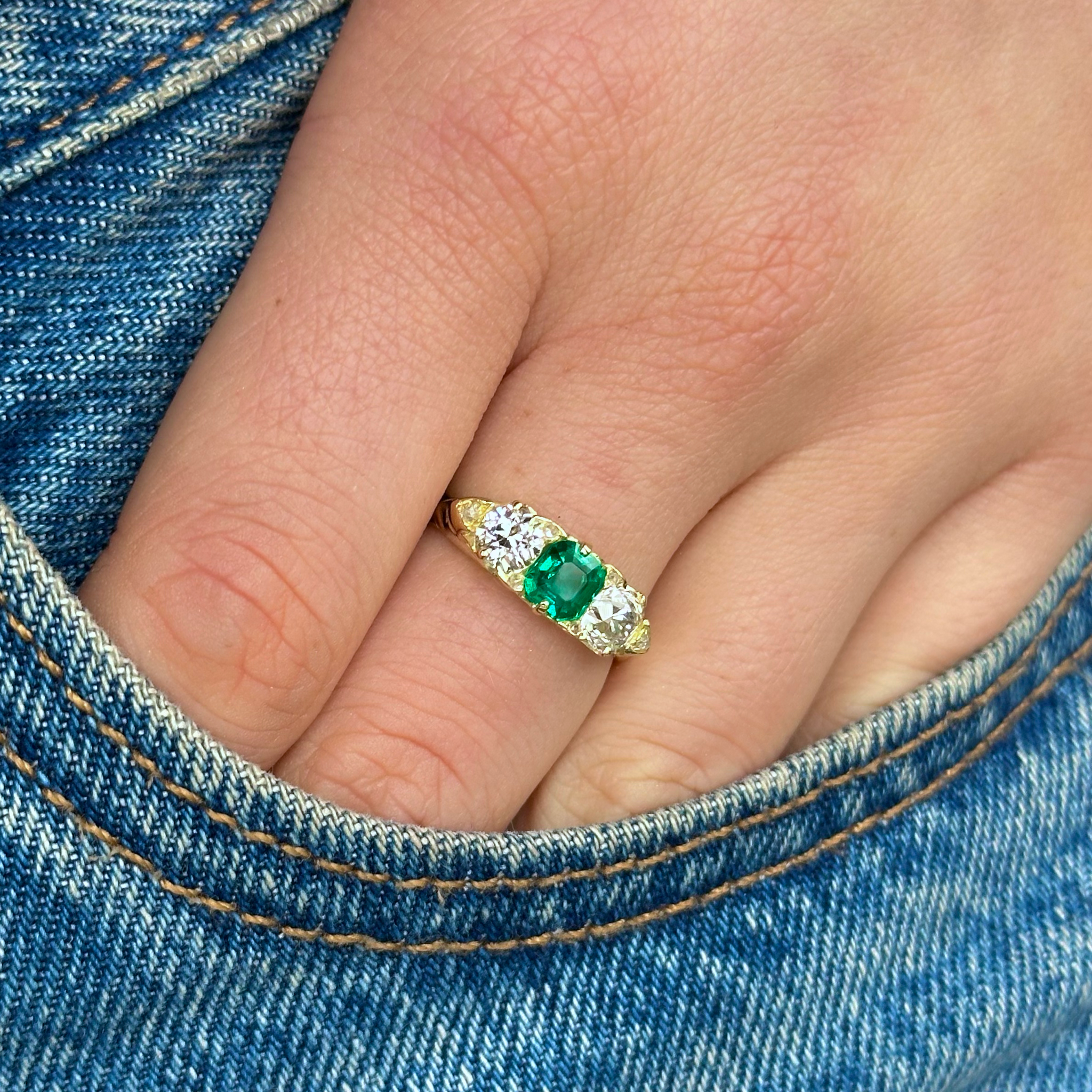 Antique emerald and diamond three stone ring, worn on hand in pocket of jeans