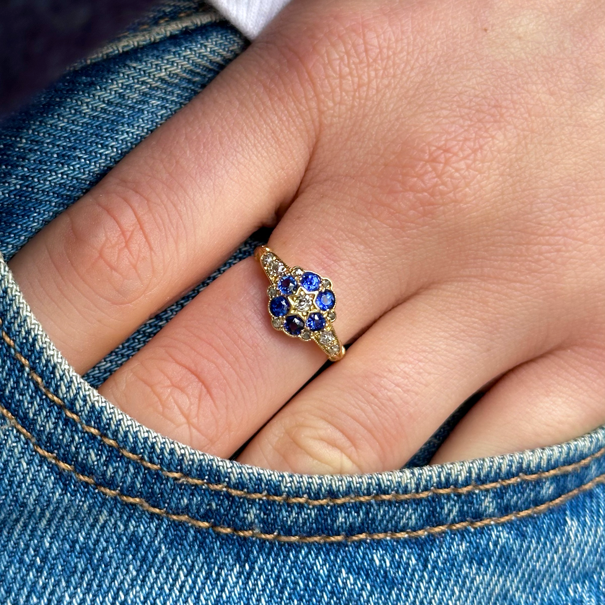 Antique Edwardian sapphire and diamond cluster ring, worn on hand in pocket of jeans