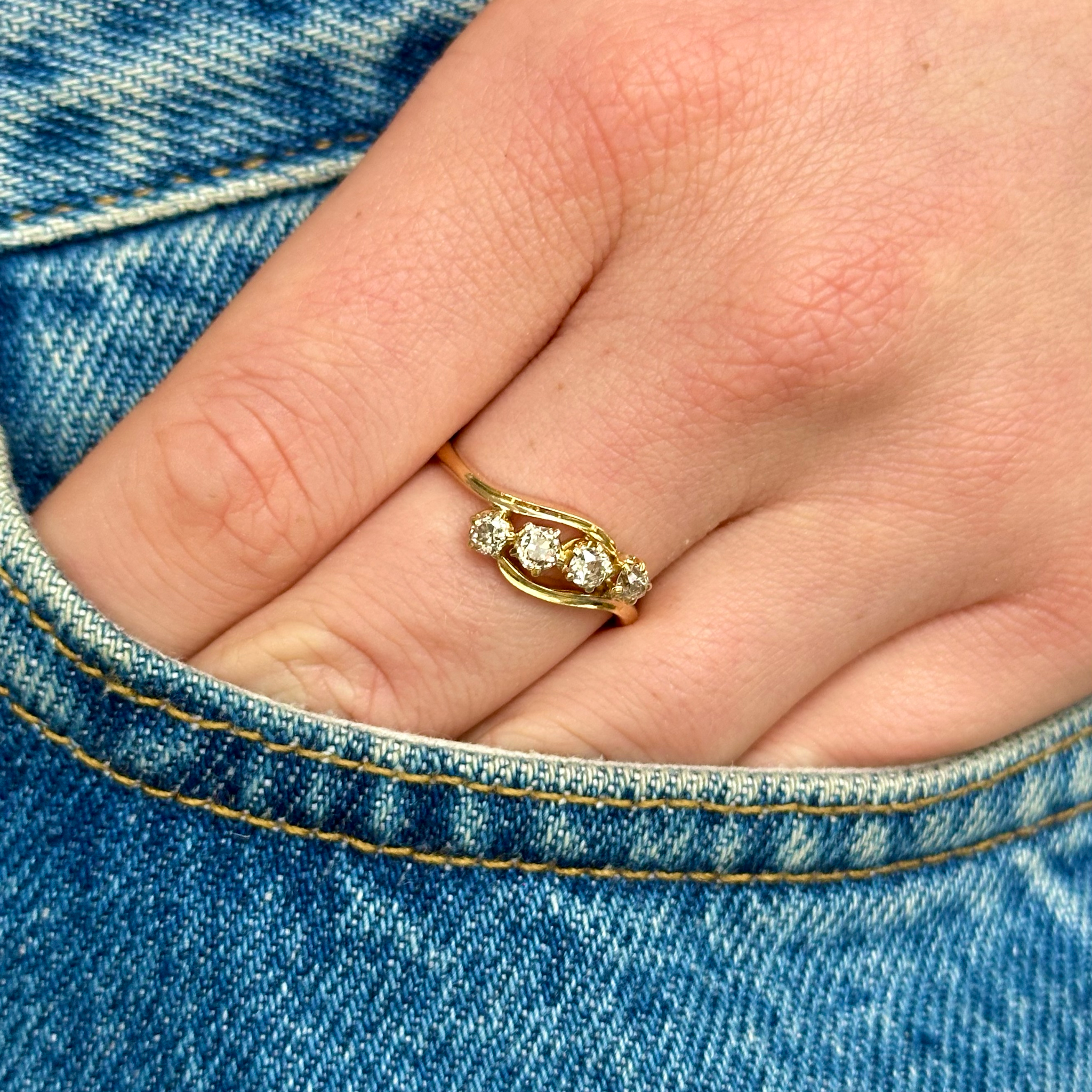 Vintage four stone diamond engagement ring, worn on hand.