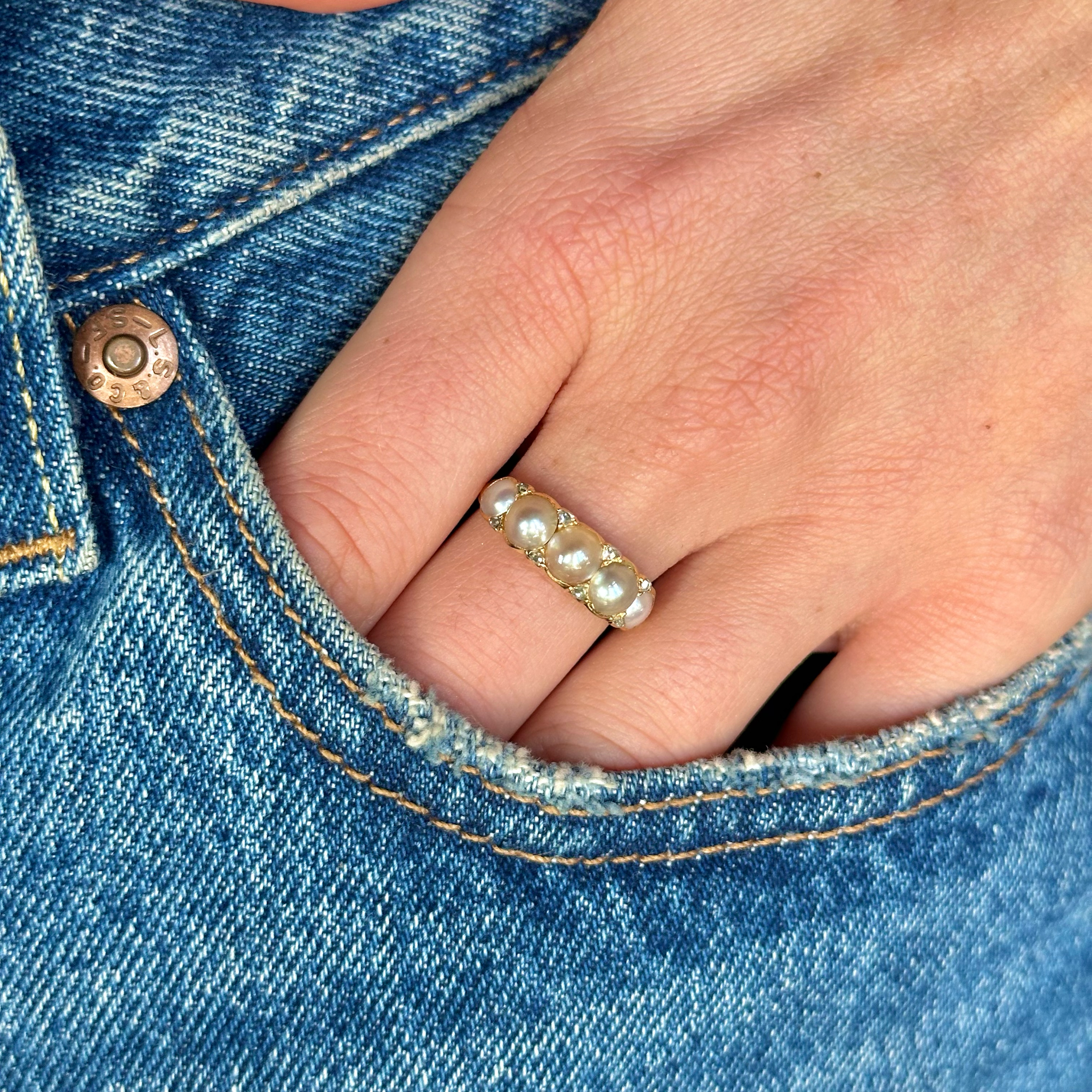 pearl half hoop ring worn on hand in pocket of jeans