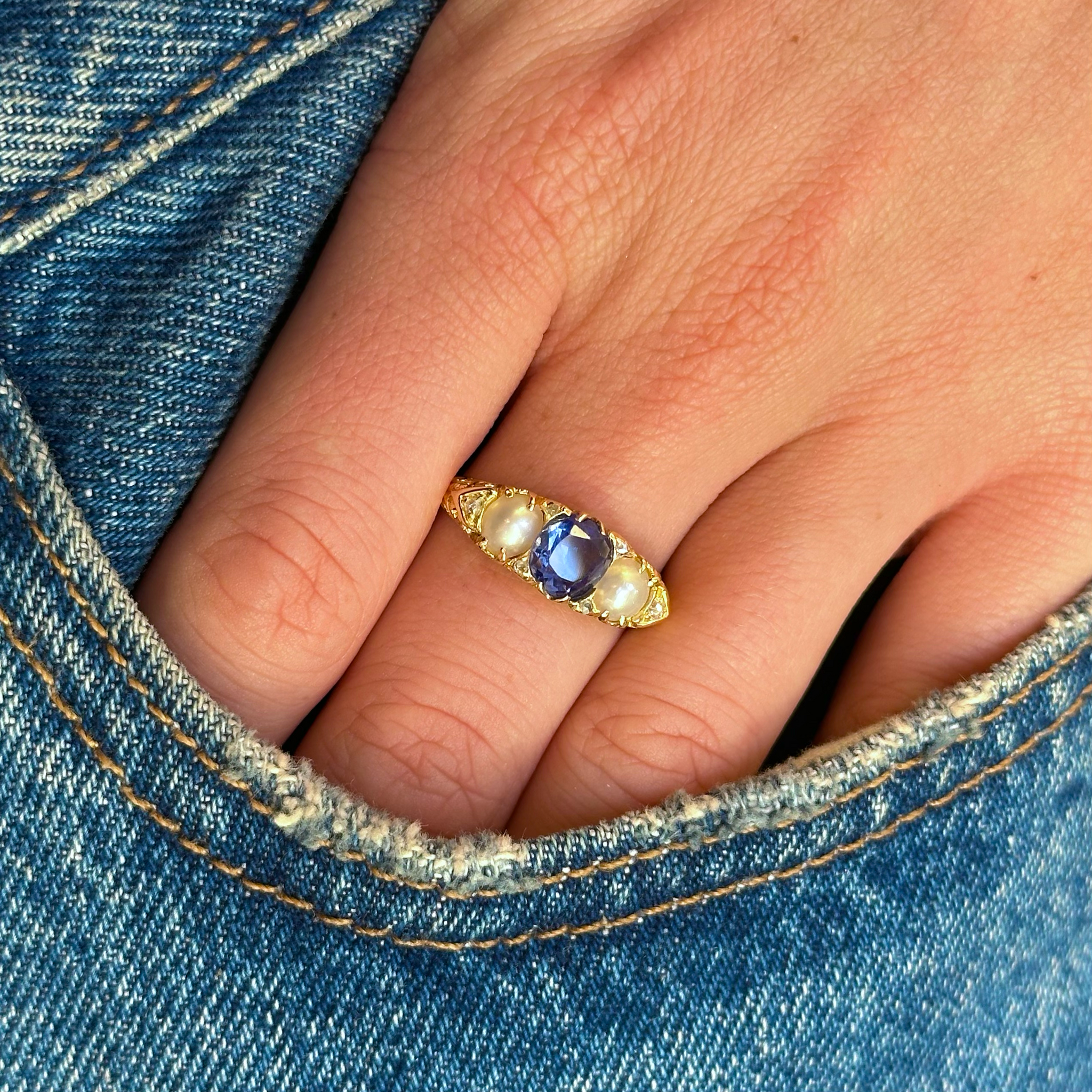 sapphire and pearl three stone ring worn on hand in pocket of jeans