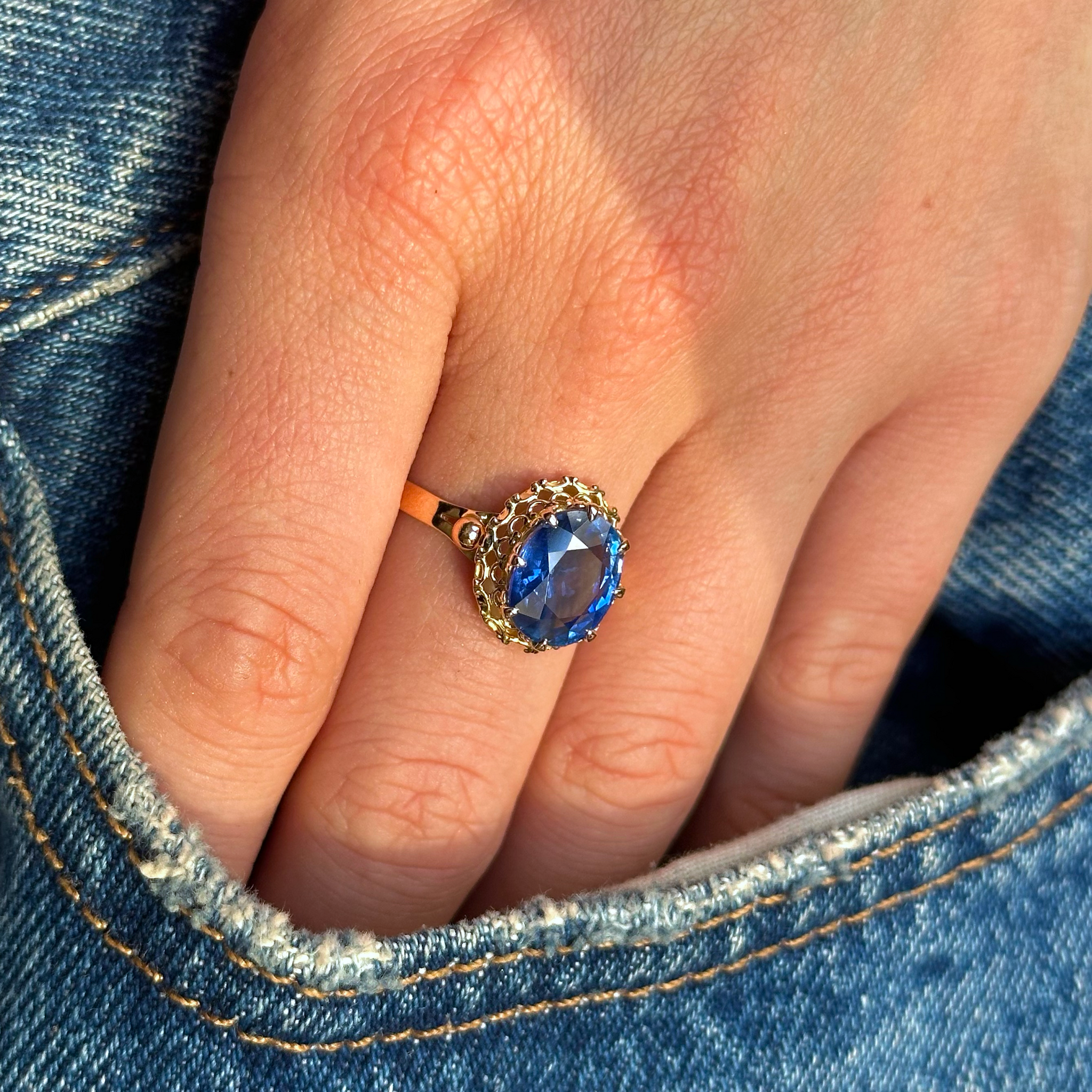 Single stone sapphire engagement ring on hand inside pocket of jeans