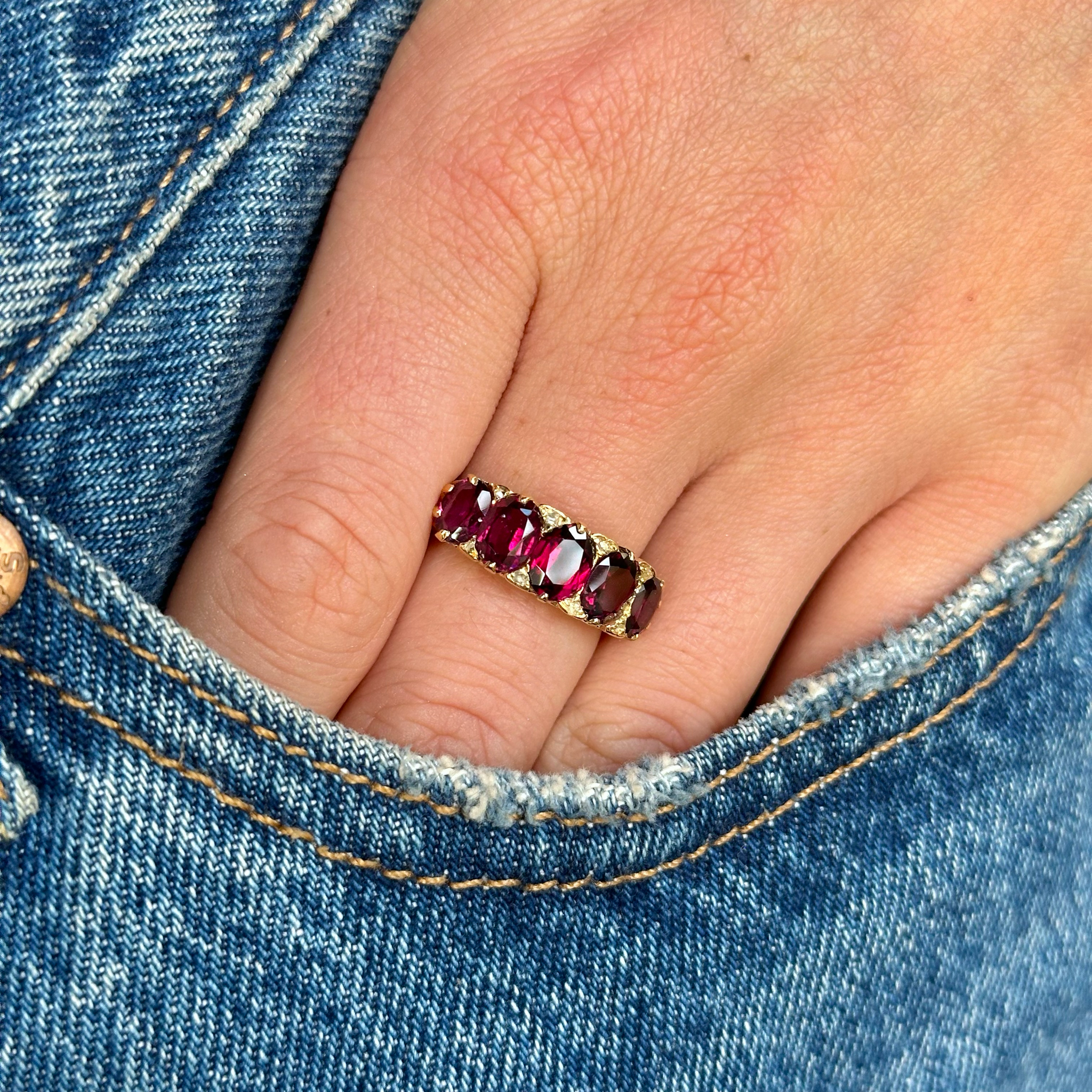 victorian five stone garnet ring worn on hand in pocket of jeans