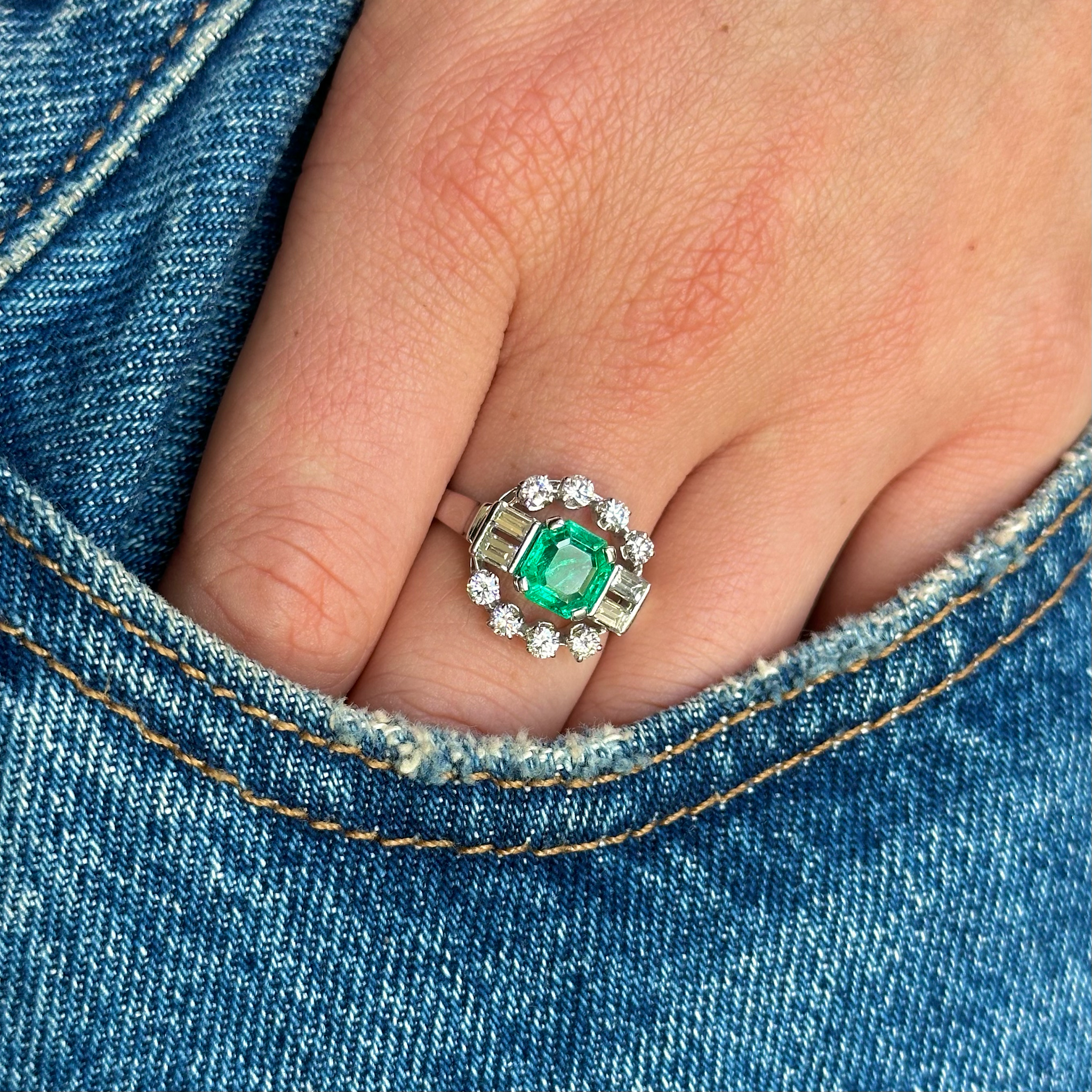 vintage diamond and emerald ring worn on hand in pocket of jeans.