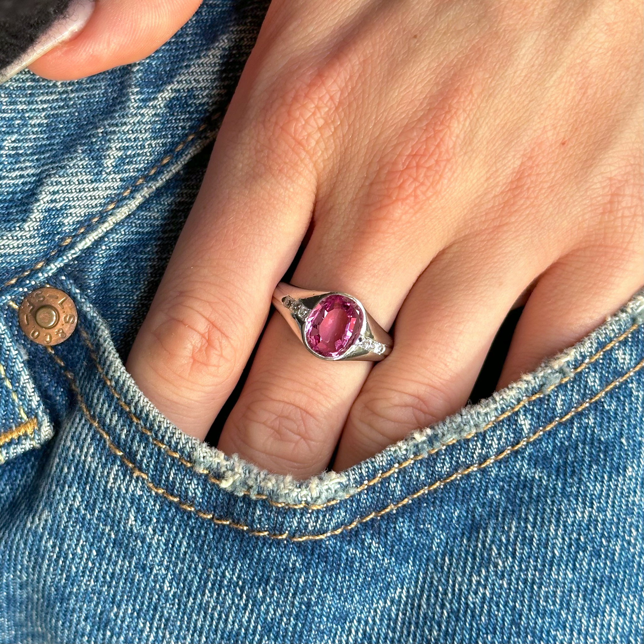 pink sapphire and diamond ring in pocket of jeans.