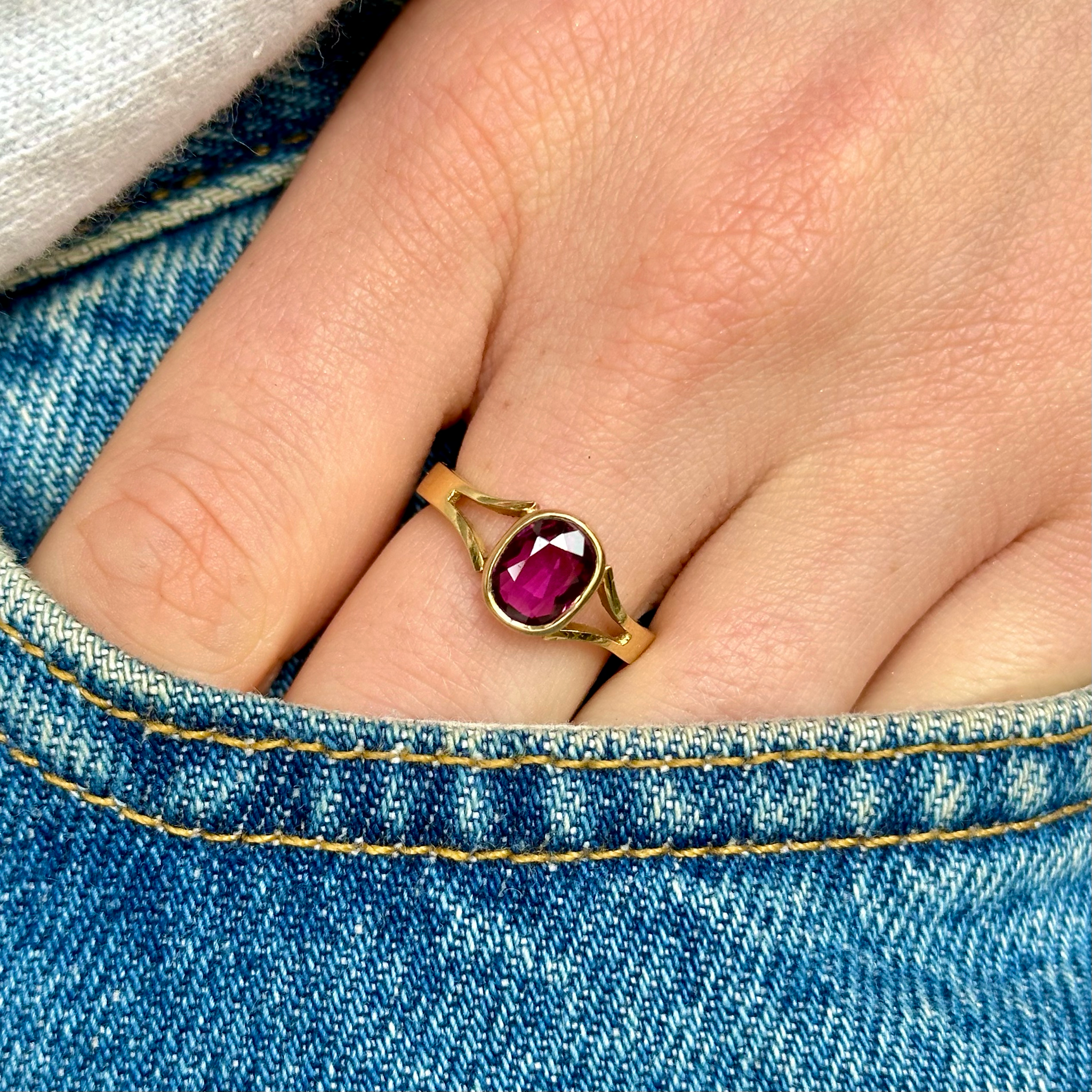 Vintage single stone ruby ring worn on hand in jeans