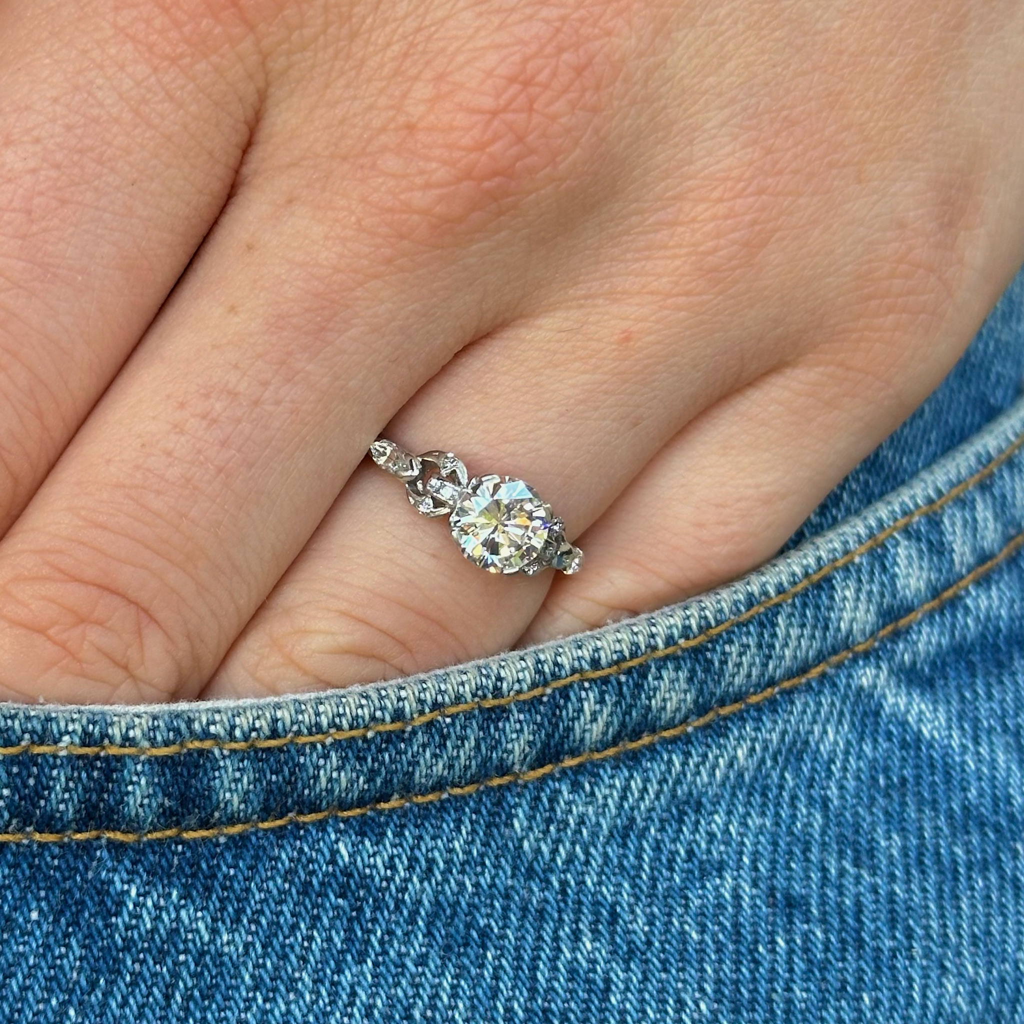 Vintage solitaire diamond engagement ring, worn on hand in pocket of jeans