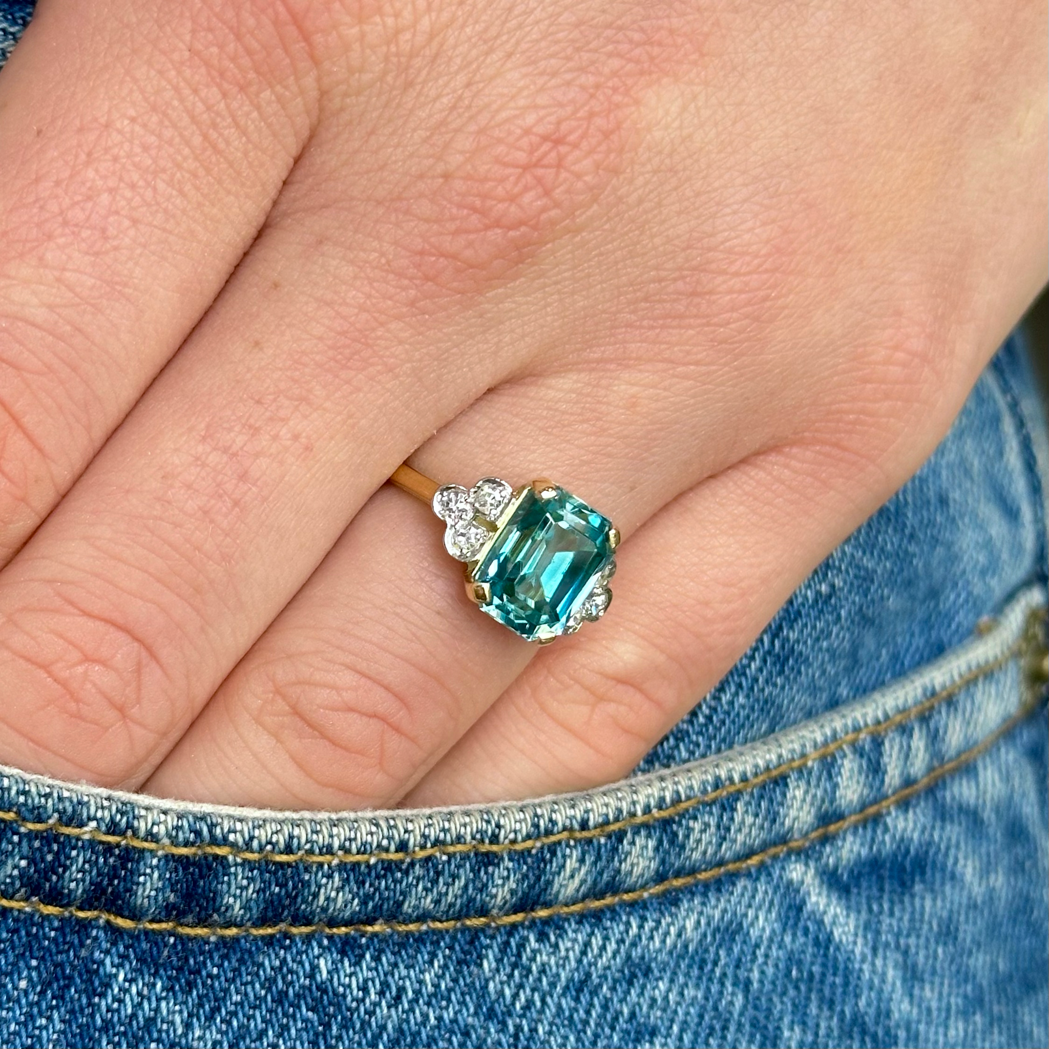 Vintage zircon and diamond engagement ring, worn on hand in pocket of jeans.