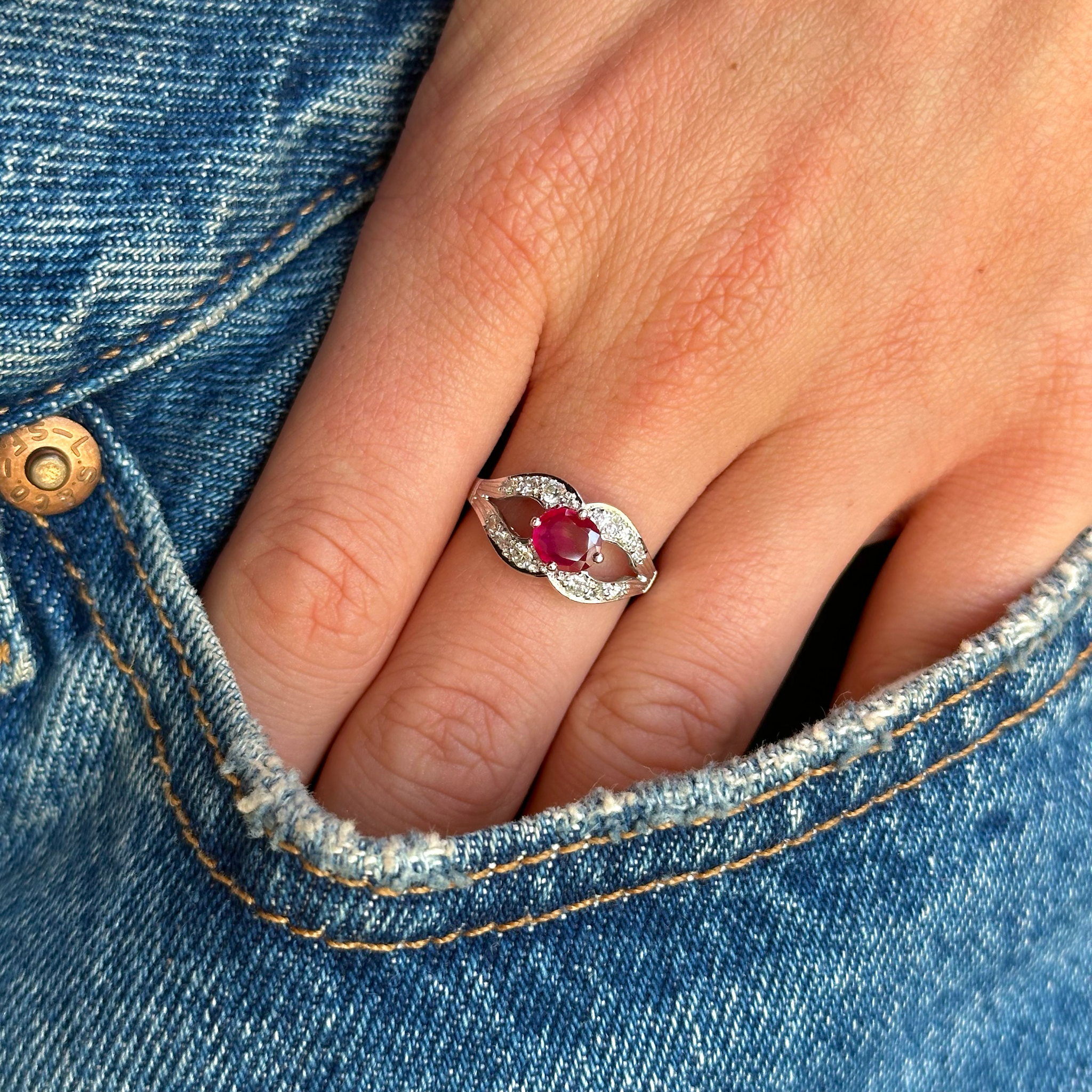 vintage ruby and diamond ring worn on hand in pocket of denim jeans.