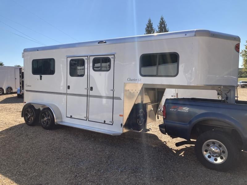 white bumper-pull horse trailer hitched to pick-up truck