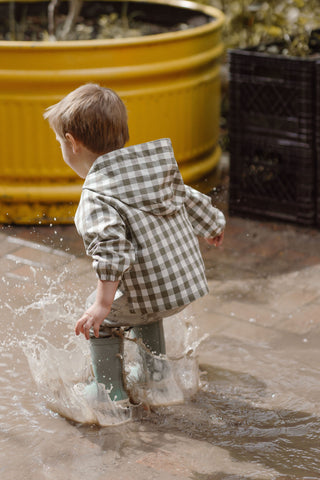 A boy jumps in puddles in the Pehr Park Jacket and Explorer Boots.