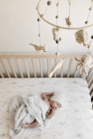 baby in crib sleeping under mobile 