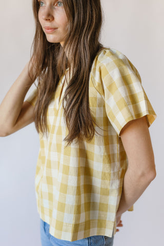 A woman wears the Checkmate Dandelion top.
