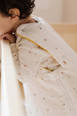 baby in sleep bag standing up in crib looking out