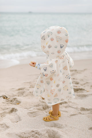 A little girl stands on the beach in her Pehr poncho towel.