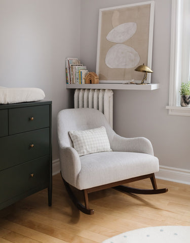 Corner of nursery with rocking chair and dresser with change station on top