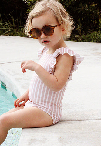 Toddler sitting at pool's edge in Ruffle One-Piece Swimsuit