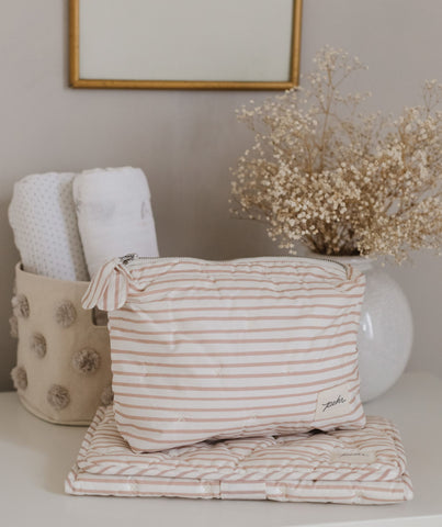 An image of the Rose Pink On The Go Mini Pouch and Change Pad, sitting on top of a dresser.