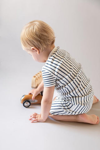 toddler in pajamas playing with toy car on floor 