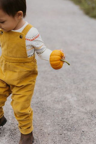 toddler yellow overalls holding pumpkin