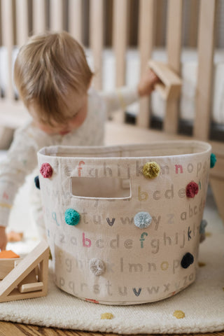 baby playing with toys near storage basket