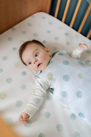 baby in crib wearing sleep bag