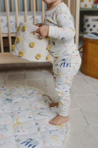 baby in pajamas holding bin in nursery