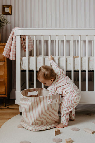 baby playing beside crib in nursery