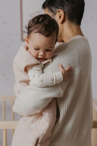 mother holding baby wearing sleep bag