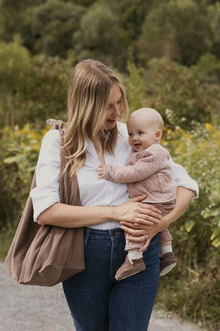 mother carrying baby outdoors 