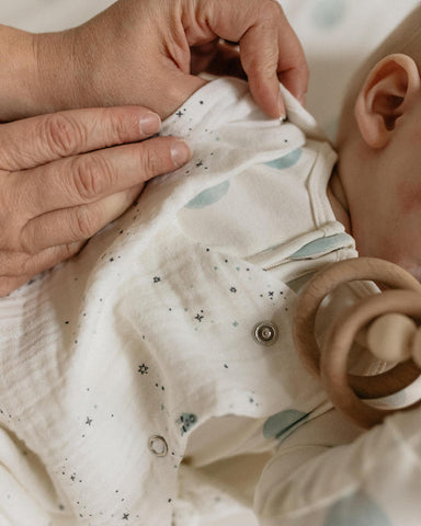 Mother putting sleep bag on baby