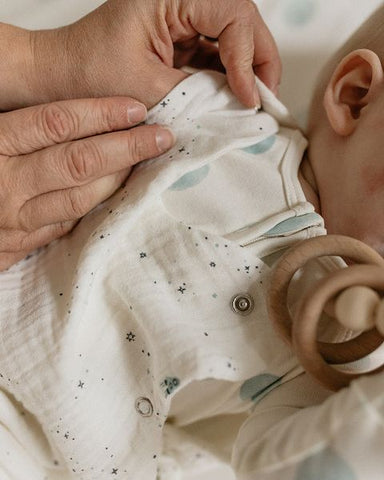 mother putting sleep bag on newborn