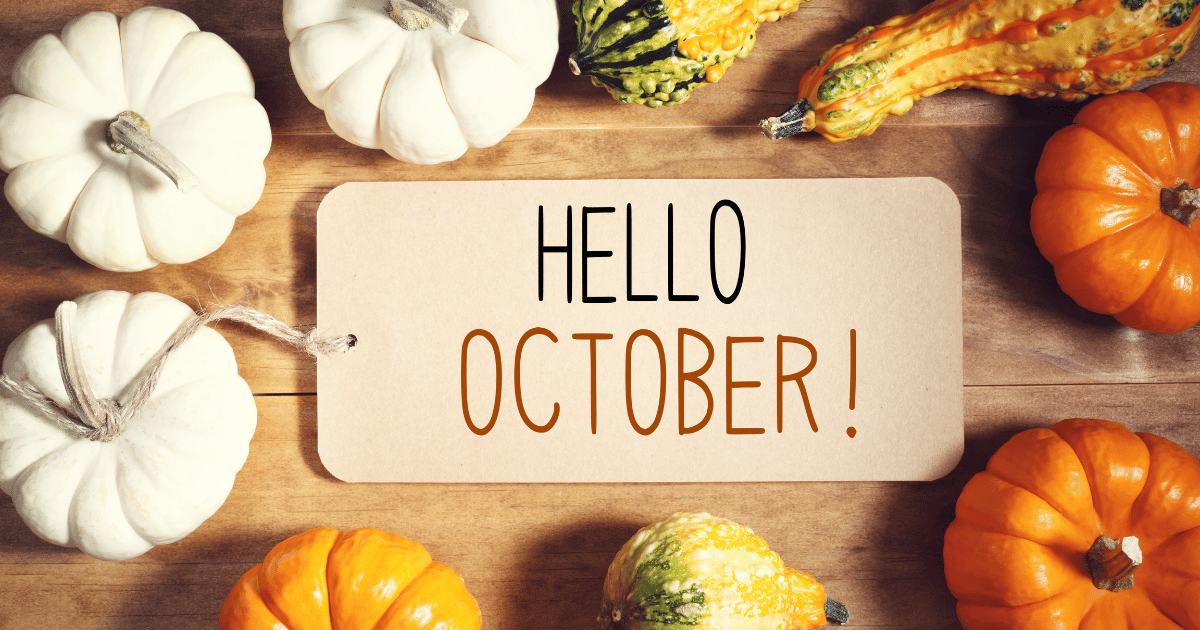 Hello October message with collection of pumpkins on wooden table.