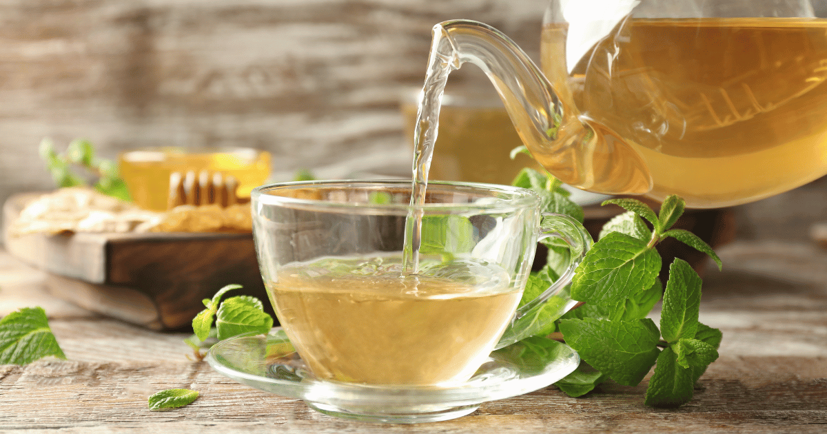 Pouring Aromatic Lemon Balm Tea into Cup on Wooden Table