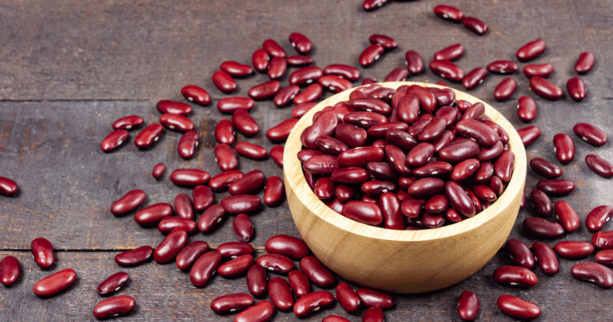 Kidney beans in a wooden bowl on a wood table.