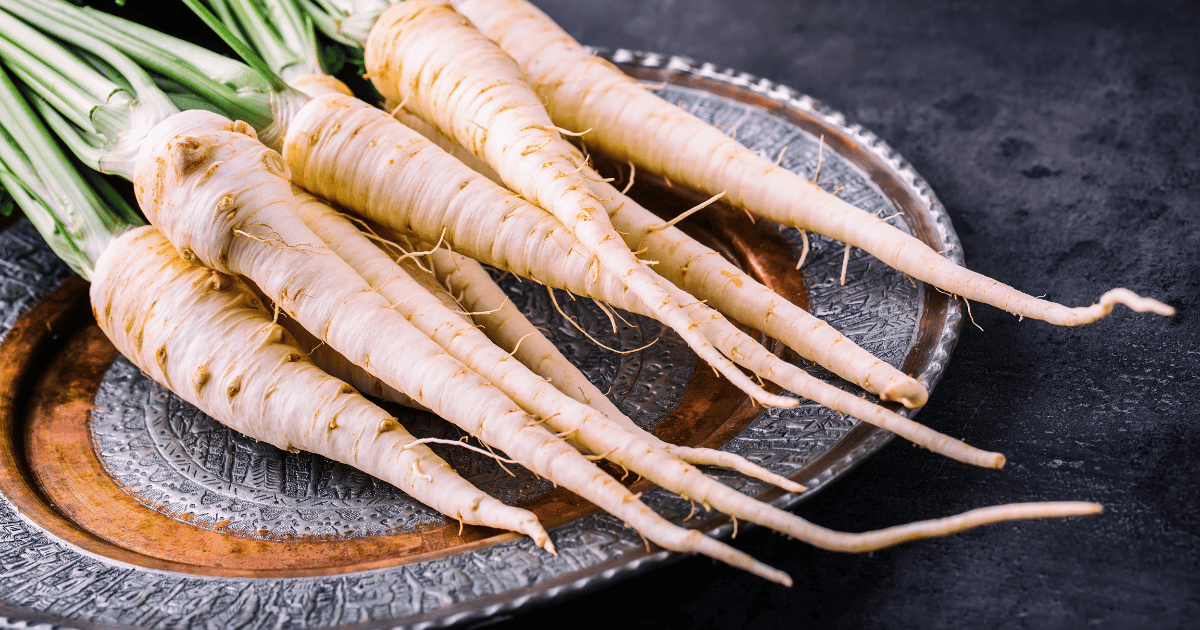 Parsnips on a metal plate and dark table.