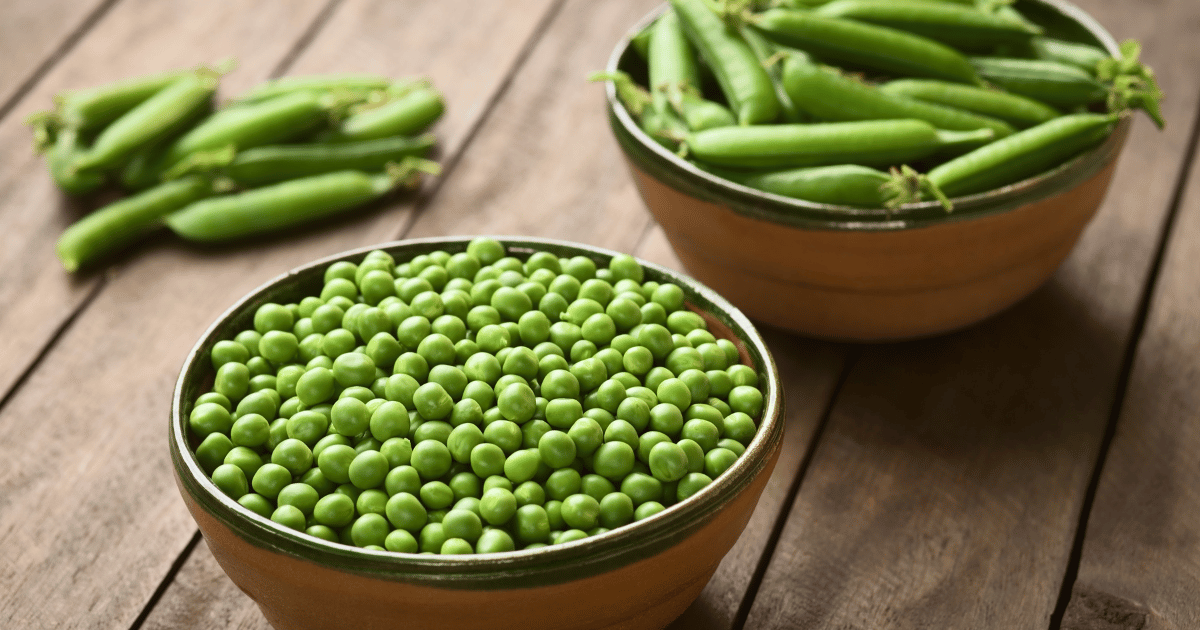 Green peas in bowls on a wooden table.