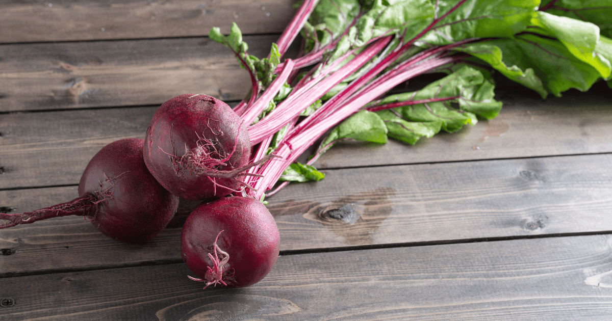 Three beets on a wooden table.