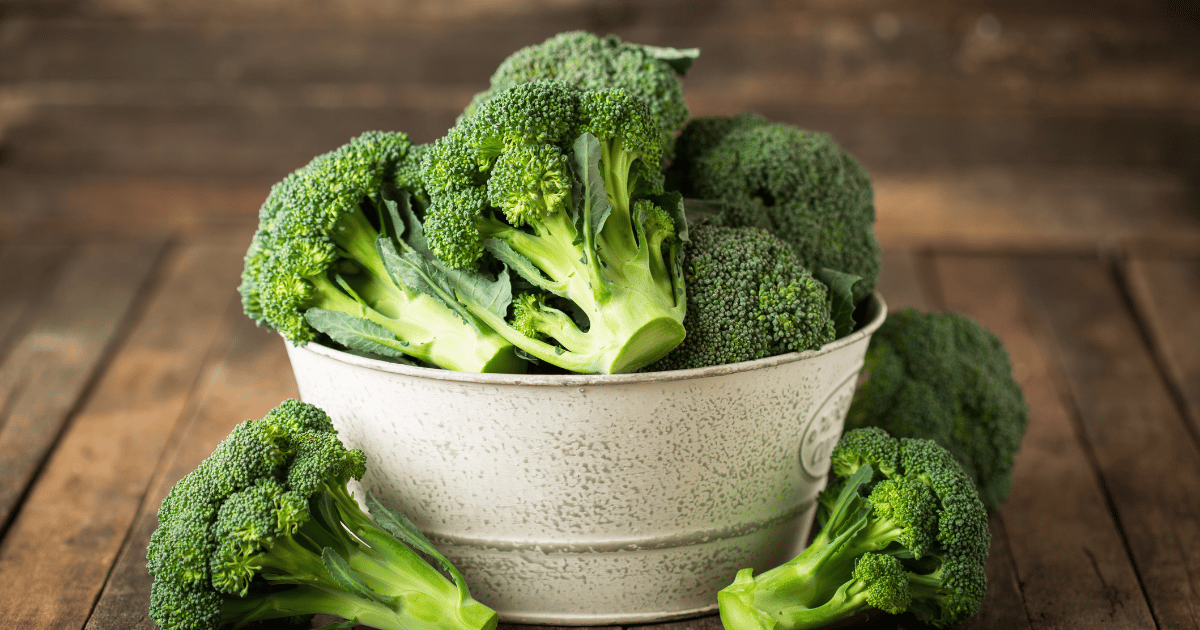 Broccoli in a bowl with a wood table and background.