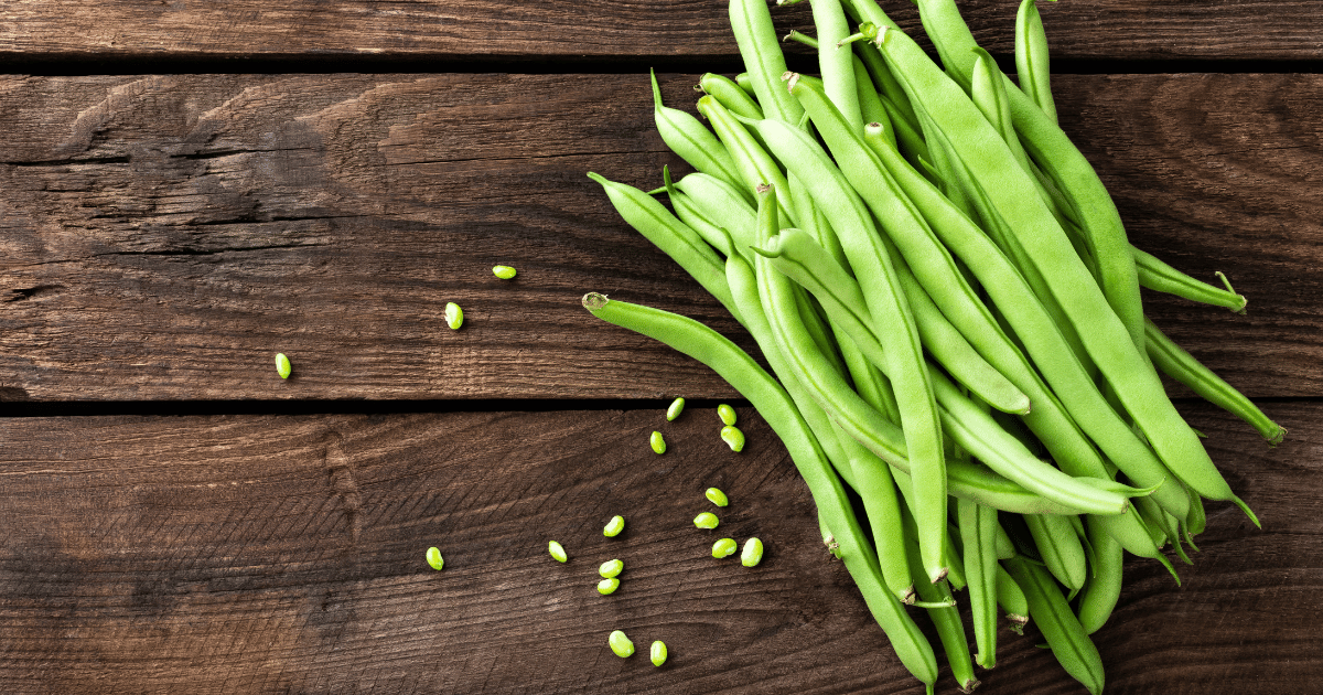 Green beans on a wooden background.