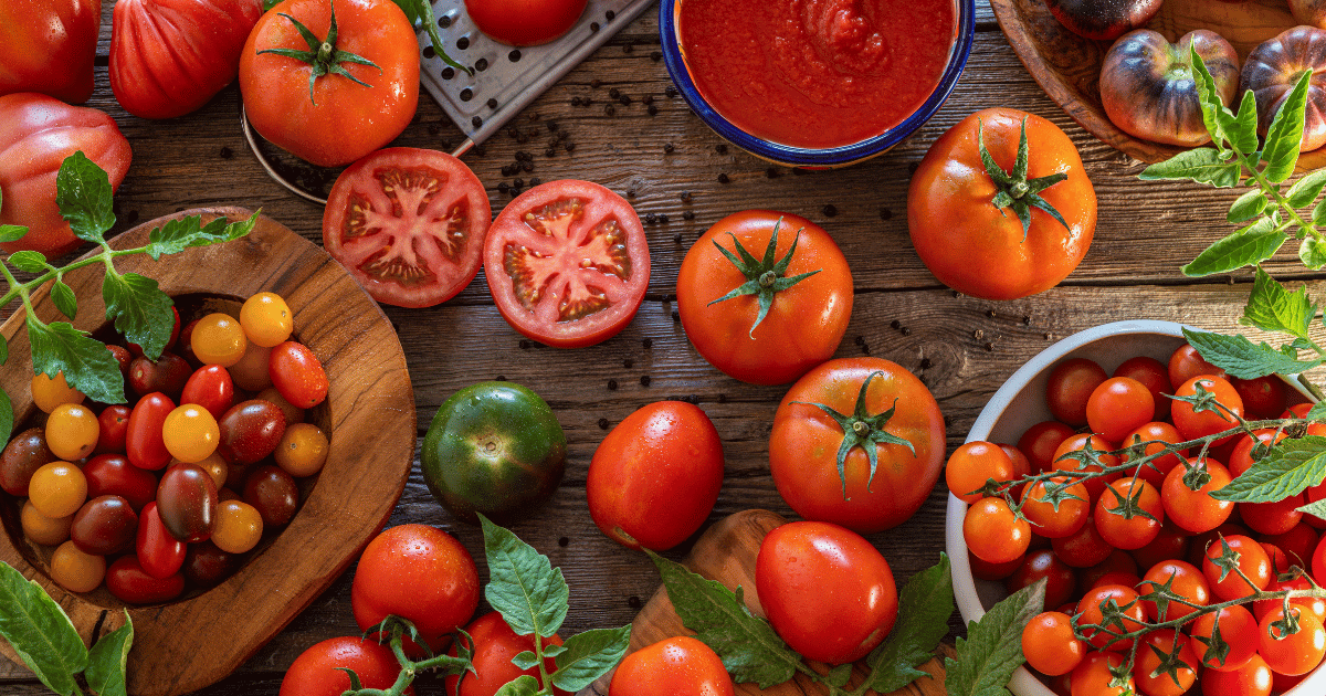 A range of different tomatoes on a wooden table.
