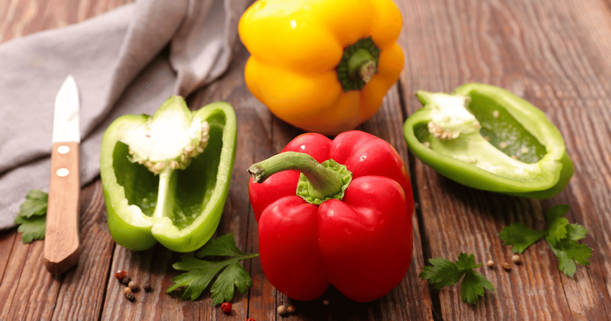 Sliced bell peppers on a wooden table with a knife.