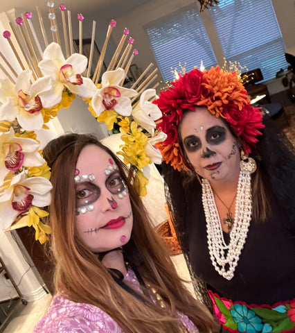 2 women dressed for dia de los muertos 2022 as catrinas with flower crowns