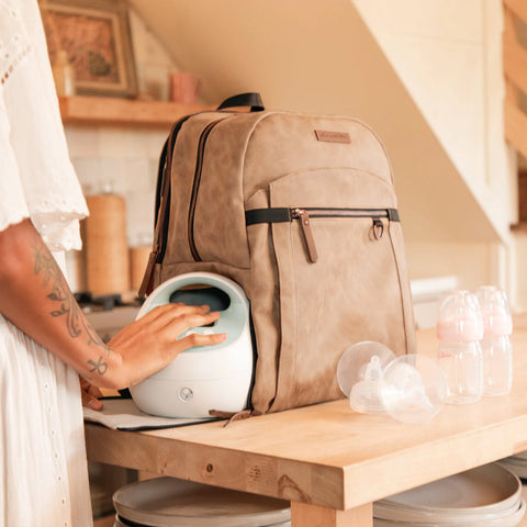 Woman placing spectra breast pump in bottom of diaper bag