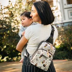 Mother carrying baby, there is a purse across her back featuring a Nightmare Before Christmas Print