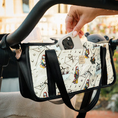 A stroller caddy hanging from stroller bars, mom is removing her phone