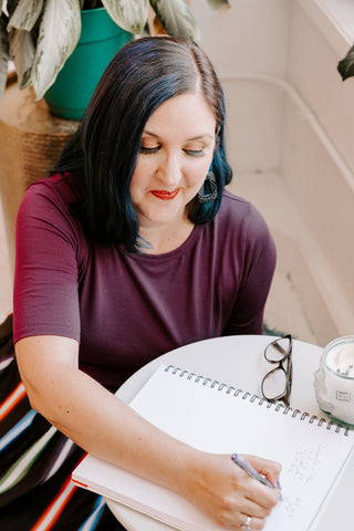 allisons sits in a purple dress at a small table writing on a notepad