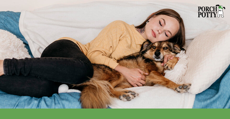 A young woman cuddles on the couch with her dog