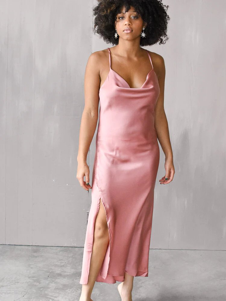 a model wearing a rose-colored silky slipdress in a gray room